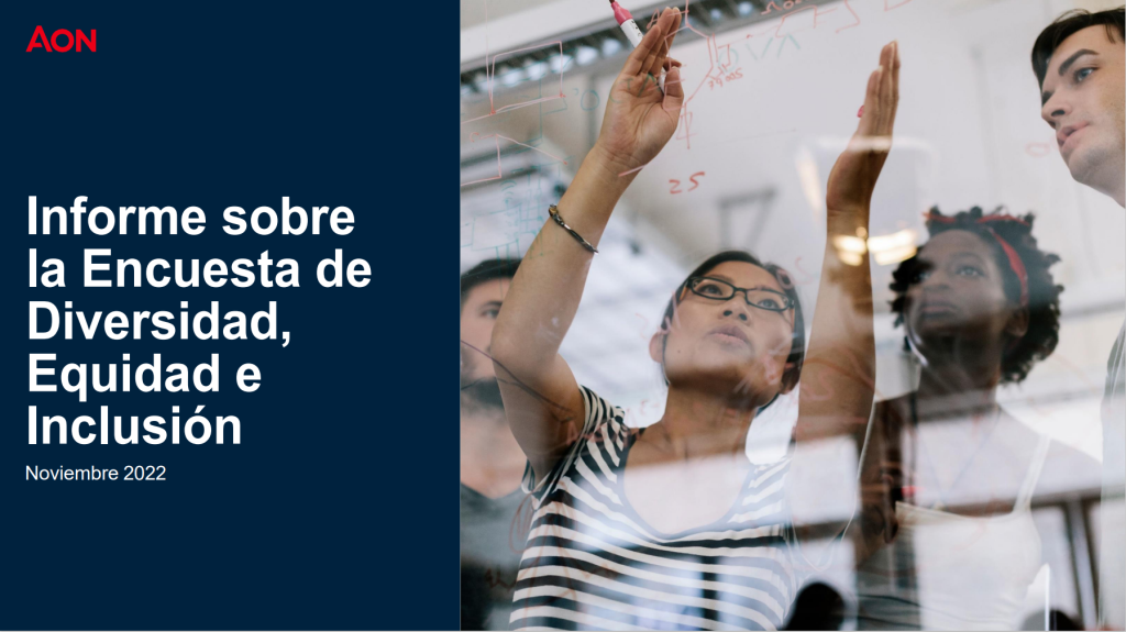 EN la imagen una mujer joven con gajas escribiendo en un tablero de vidrio y sus compañeros de trabajo prestando atención.